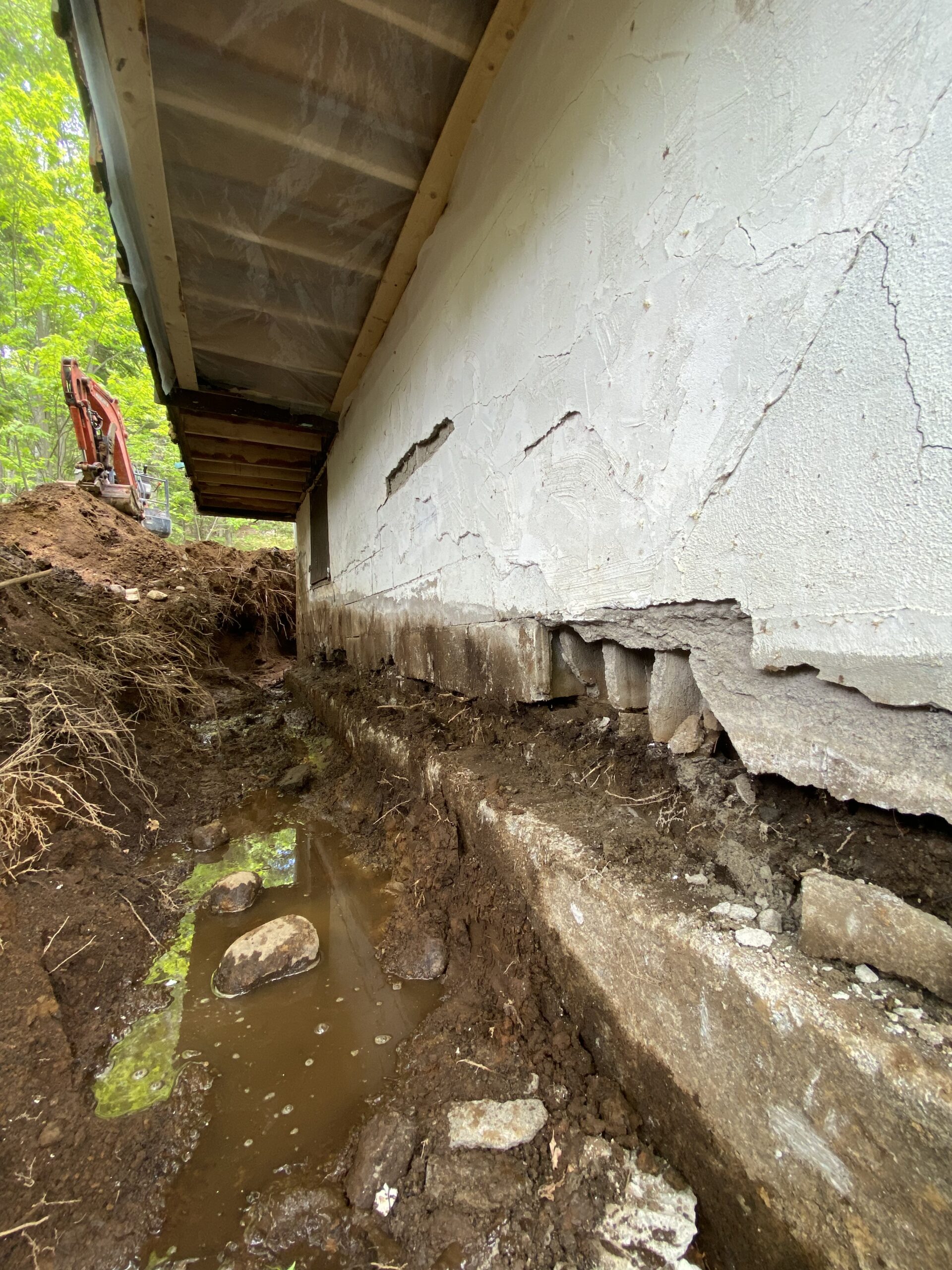 Fondation détériorée dont le béton s’effrite au pied du mur