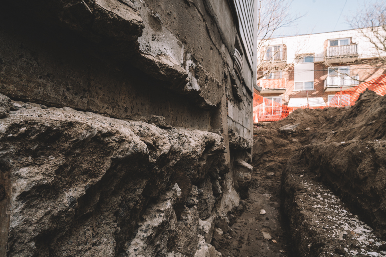 Open trench along a foundation during a French drain replacement